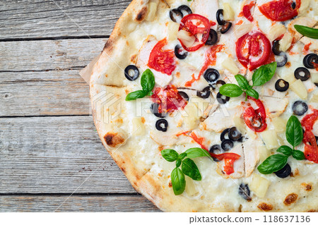 Pizza with mozzarella cheese , olives , chicken , pineapple , basil and tomatoes 118637136