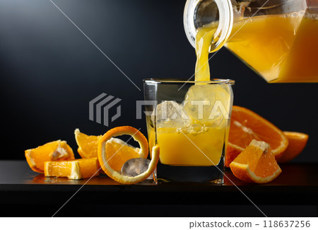 Glass of orange juice with ice on a black background. Glass of orange juice with ice on a black background. 118637256