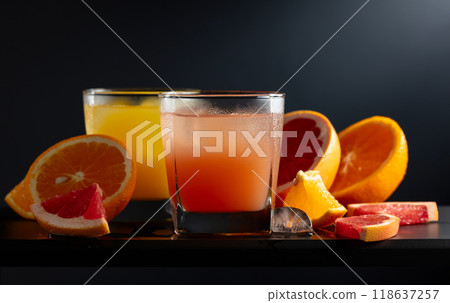 Glasses of grapefruit and orange juice with ice on a black background. Glasses of grapefruit and orange juice with ice on a black background. 118637257