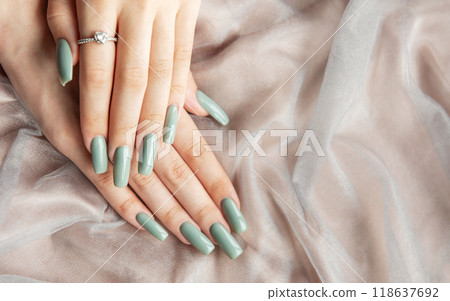 Elegant hands with long green nails resting on soft fabric Elegant hands with long green nails resting on soft fabric 118637692
