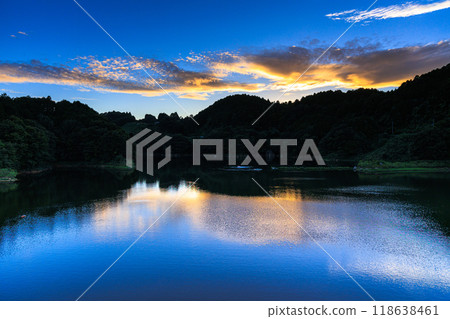 奈良市東部布雲水壩的初秋傍晚景色，金黃色的雲朵在水壩湖對岸的山腰和倒映在湖面上的金雲閃閃發光。 118638461
