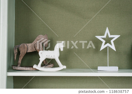Wooden rocking horse are on a shelf against a green wall Wooden rocking horse are on a shelf against a green wall 118638757