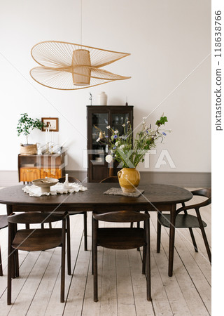 Large oval table with a yellow vase of flowers in the center, surrounded by brown chairs Large oval table with a yellow vase of flowers in the center, surrounded by brown chairs 118638766