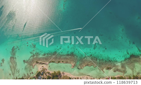 Aerial top down view speedboat leaving white trail on turquoise crystal water lagoon, boat riding across coral reef line shore. Tropical island beach. Perfect exotic summer travel vacation background Aerial top down view speedboat leaving white trail on turquoise crystal water lagoon, boat riding across coral reef line shore. Tropical island beach. Perfect exotic summer travel vacation background 118639713
