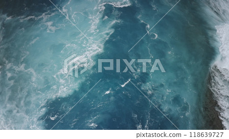 Aerial top down view blue ocean waves splashing foam. Dramatic deep water crashing sea coast. The stunning colors of the powerful storm high tide ocean surface seascape. Natural background. Drone shot Aerial top down view blue ocean waves splashing foam. Dramatic deep water crashing sea coast. The stunning colors of the powerful storm high tide ocean surface seascape. Natural background. Drone shot 118639727