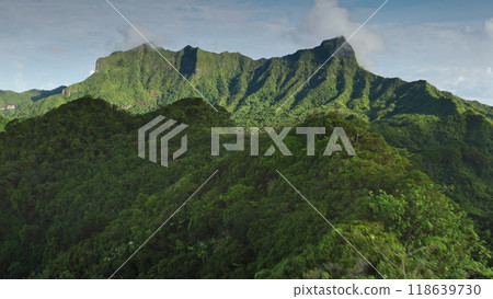Aerial flight over tropical Bora Bora island green lush rainforest mountain. Mount Otemanu range edge under clouds blue sky. Remote wild nature , exotic summer travel. Drone shot natural background Aerial flight over tropical Bora Bora island green lush rainforest mountain. Mount Otemanu range edge under clouds blue sky. Remote wild nature , exotic summer travel. Drone shot natural background 118639730