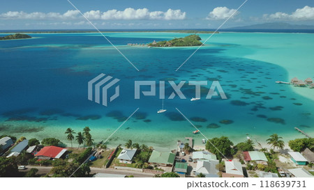 Two sailboats sailing turquoise water near luxury beach resort in Bora Bora, French Polynesia. Lush green vegetation covers the small islands. Perfect summer travel vacation background. Aerial view Two sailboats sailing turquoise water near luxury beach resort in Bora Bora, French Polynesia. Lush green vegetation covers the small islands. Perfect summer travel vacation background. Aerial view 118639731
