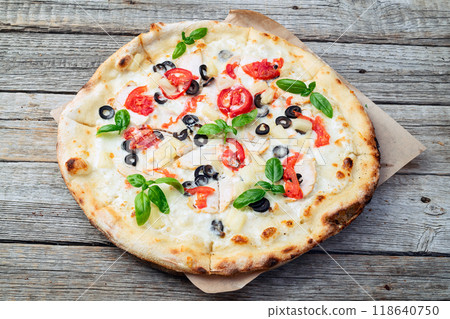 Pizza with mozzarella cheese , olives , chicken , pineapple , basil and tomatoes 118640750