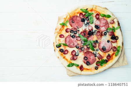 Pizza with mozzarella cheese , salami sausages , olives , and basil 118640751