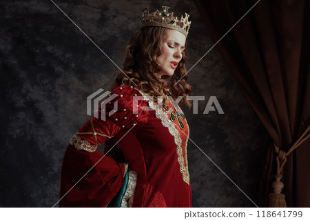 tired medieval queen in red dress with crown having backache tired medieval queen in red dress with crown having backache 118641799