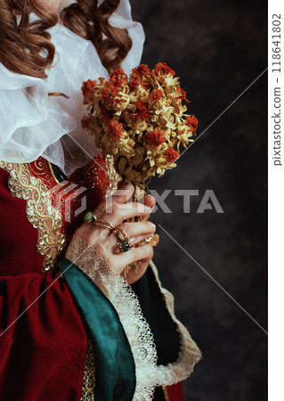 Closeup on medieval queen in red dress with dried flower 118641802