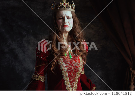 unhappy medieval queen in red dress with white makeup 118641812