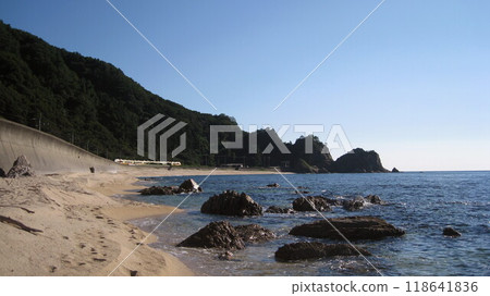The Inaho Express train runs along the scenic Sasagawa Nagare coastline, the Sea of Japan and white sand with a clear blue sky. 118641836