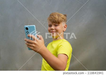An attractive boy is smiling using his phone. An attractive boy is smiling using his phone. 118641941