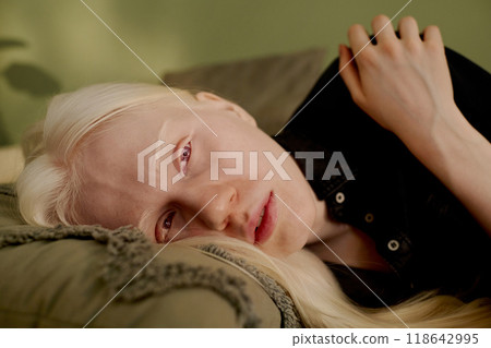 Closeup of modern young Caucasian woman with albinism lying on couch in morning 118642995
