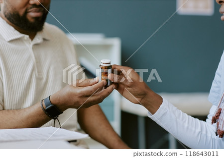 Close-up of hands exchanging medication bottle, indicating supportive gesture in medical or caregiving context. Image portrays interaction in a healthcare or caregiving environment Close-up of hands exchanging medication bottle, indicating supportive gesture in medical or caregiving context. Image portrays interaction in a healthcare or caregiving environment 118643011