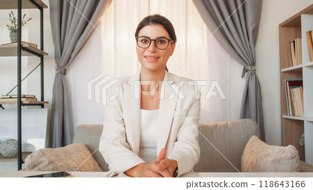 Business training. Female coach. Educational courses. Happy elegant woman sitting sofa in cozy light office room interior. Business training. Female coach. Educational courses. Happy elegant woman sitting sofa in cozy light office room interior. 118643166