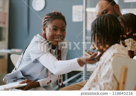 Healthcare professional engaging child in medical setting, demonstrating care and attentiveness while family member observing interaction closely in clinical environment Healthcare professional engaging child in medical setting, demonstrating care and attentiveness while family member observing interaction closely in clinical environment 118643216