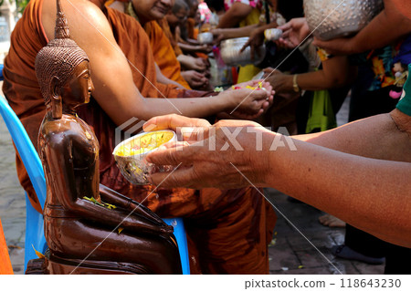 During Songkran, people engage in a traditional ritual of pouring water on Buddha statues as a mark of respect. 4 118643230