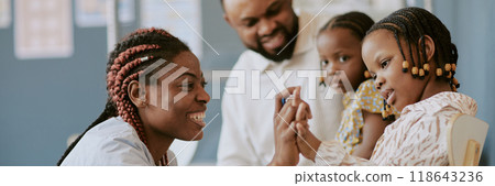 Smiling woman engaging with child while others observe in classroom environment, showcasing connection and interaction. Suitable for educational and family-oriented contexts 118643236