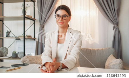 Office interview. Female chief. Business meeting. Confident smiling elegant woman sitting cozy light office room interior. 118643293