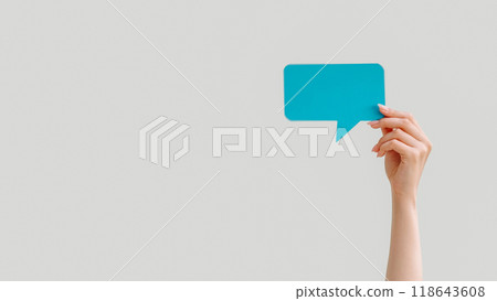 Empty speech bubble. Mobile chat. Online communication. Female hand showing blue dialogue icon mockup for text isolated on light copy space background. 118643608