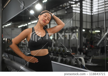 Sporty young woman stretching neck or warming up to get ready for exercise in gym 118643721