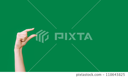 Small gesture. Finger measuring. Little bit. Female hand showing tiny size something invisible isolated on green empty space background. 118643825