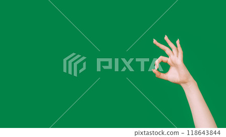 Approval sign. Okay gesture. Good feedback. Deal agreement. Female hand recommending with OK signal isolated on green empty space background. Approval sign. Okay gesture. Good feedback. Deal agreement. Female hand recommending with OK signal isolated on green empty space background. 118643844
