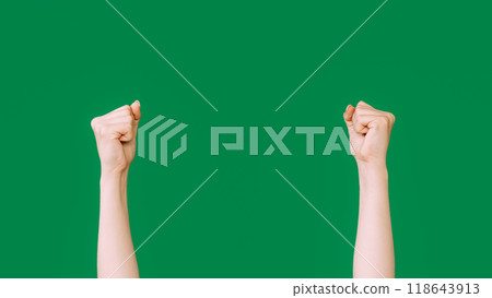 Raised fists. Protest gesture. Rebellion symbol. Female clenched hands striking knocking isolated on green empty space background. Raised fists. Protest gesture. Rebellion symbol. Female clenched hands striking knocking isolated on green empty space background. 118643913