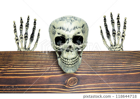 The human skeleton is sitting on a wooden table with its scary smile on a white background. The human skeletons, devil, evil, or satan seem to be watching or waiting for something. The scene is eerie The human skeleton is sitting on a wooden table with its scary smile on a white background. The human skeletons, devil, evil, or satan seem to be watching or waiting for something. The scene is eerie 118644718