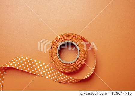A roll of orange ribbon with white polka dots on it A roll of orange ribbon with white polka dots on it 118644719