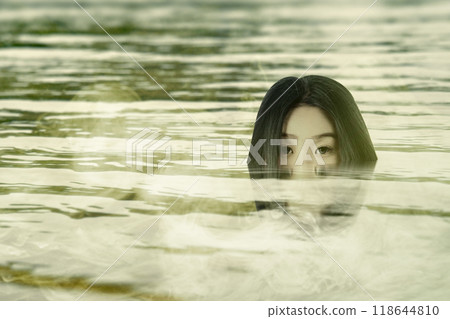 A woman ghost or witch is shown on the swamp water surface. Witch, evil, demon, satan figure. Scary and spooky horror scene A woman ghost or witch is shown on the swamp water surface. Witch, evil, demon, satan figure. Scary and spooky horror scene 118644810