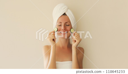 Natural beauty portrait of happy smiling young woman covers her clean skin holds slices of cucumber Natural beauty portrait of happy smiling young woman covers her clean skin holds slices of cucumber 118645233