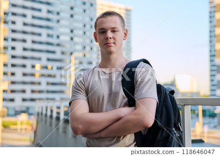 Portrait of young teenage guy looking at camera outdoors, modern skyscrapers background Portrait of young teenage guy looking at camera outdoors, modern skyscrapers background 118646047