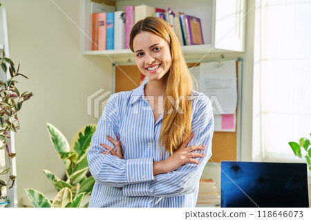 Portrait of smiling female teenager looking at camera with crossed arms in home 118646073