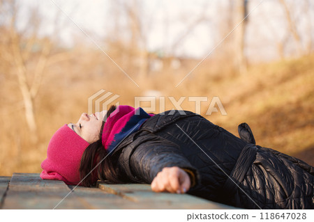 A young woman lying on a table in the garden A young woman lying on a table in the garden 118647028