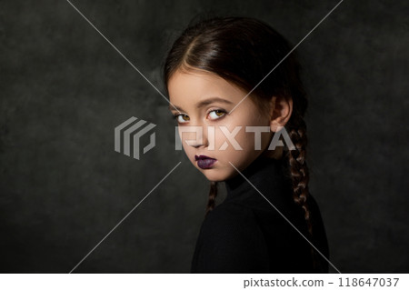 A creepy girl with a piercing dangerous look with braided braids in a black dress 118647037