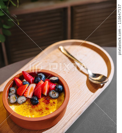 Delicious creme brulee topped with fresh berries sitting on wooden tray 118647537