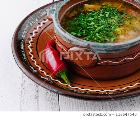 Traditional ukrainian cabbage soup with parsley and red chili pepper on white wooden table background 118647546