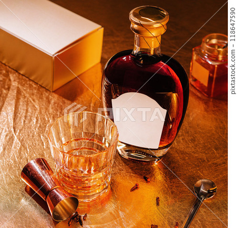 Bottle of liquor with blank label and a glass of alcohol on gold background Bottle of liquor with blank label and a glass of alcohol on gold background 118647590