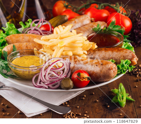 Grilled sausages served on plate with french fries, ketchup and mustard Grilled sausages served on plate with french fries, ketchup and mustard 118647829