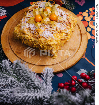 Festive napoleon cake with physalis decoration on wooden board 118647892