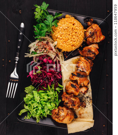 Grilled chicken shish kebab served on black plate with garnish 118647959