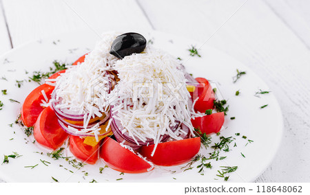 Shopska salad with tomatoes, onion, cheese, and olive sitting on white table 118648062