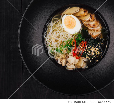 Steaming bowl of chicken ramen on black table setting 118648360