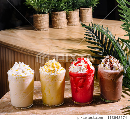 Four colorful milkshakes topped with whipped cream sitting on a stone table 118648374