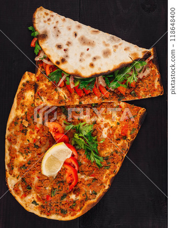 Traditional turkish lahmacun with minced meat and vegetables on dark wooden background Traditional turkish lahmacun with minced meat and vegetables on dark wooden background 118648400