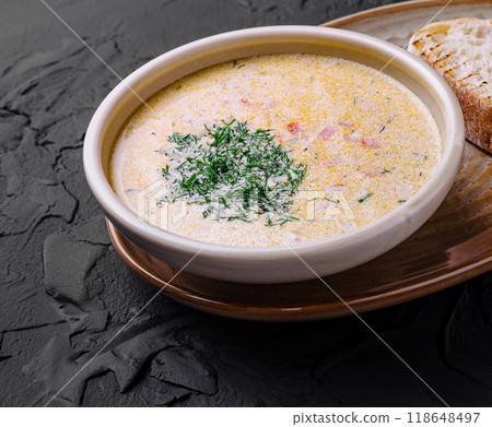 Creamy fish soup served in bowl with bread and grilled lemon on dark background Creamy fish soup served in bowl with bread and grilled lemon on dark background 118648497