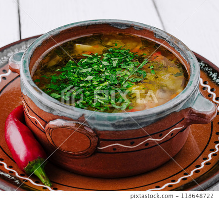 Traditional ukrainian cabbage soup with parsley and red chili pepper on white wooden table background 118648722